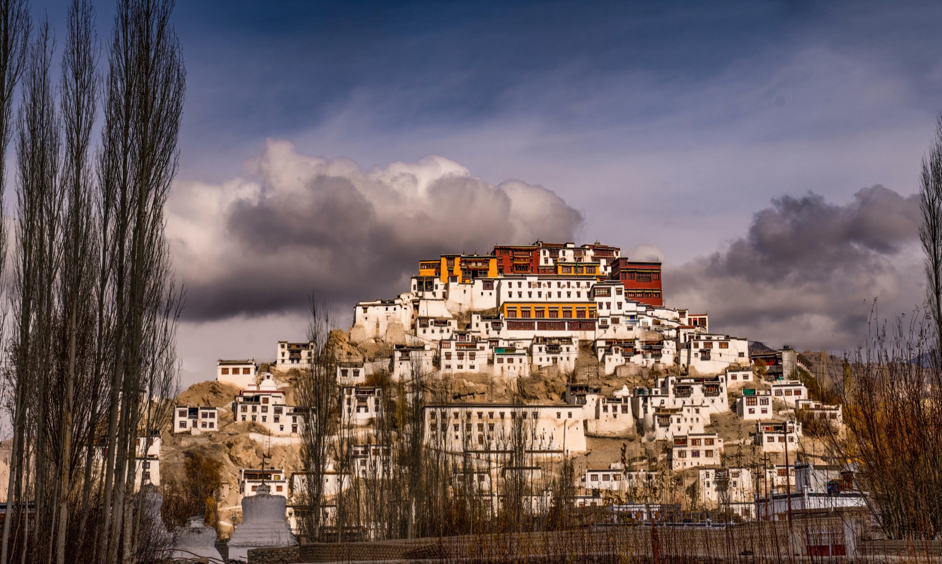 Thiksey Monastery perched on a hillside under dramatic clouds