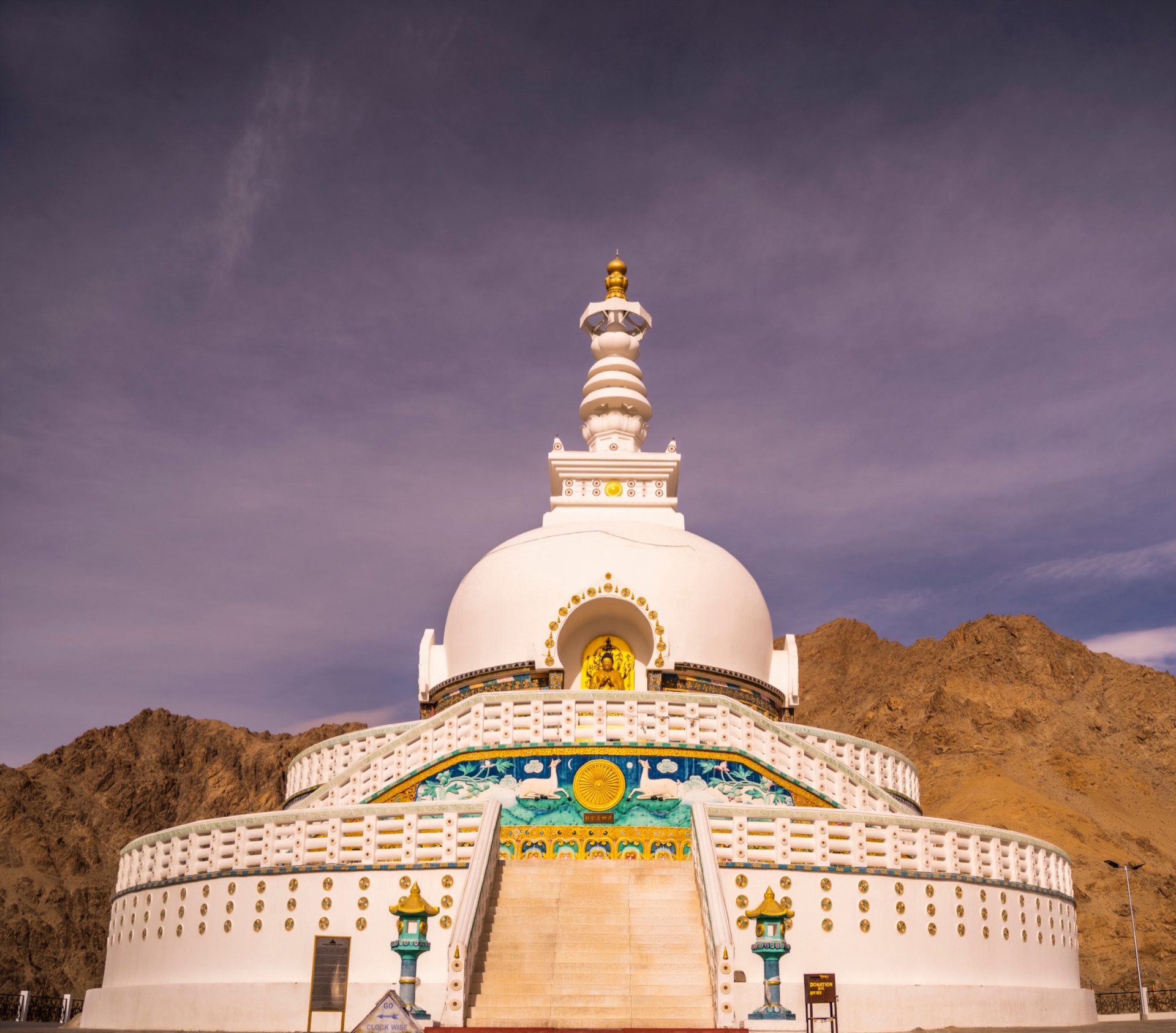 Shanti Stupa gleaming white against a purple sky with Ladakhi mountains behind